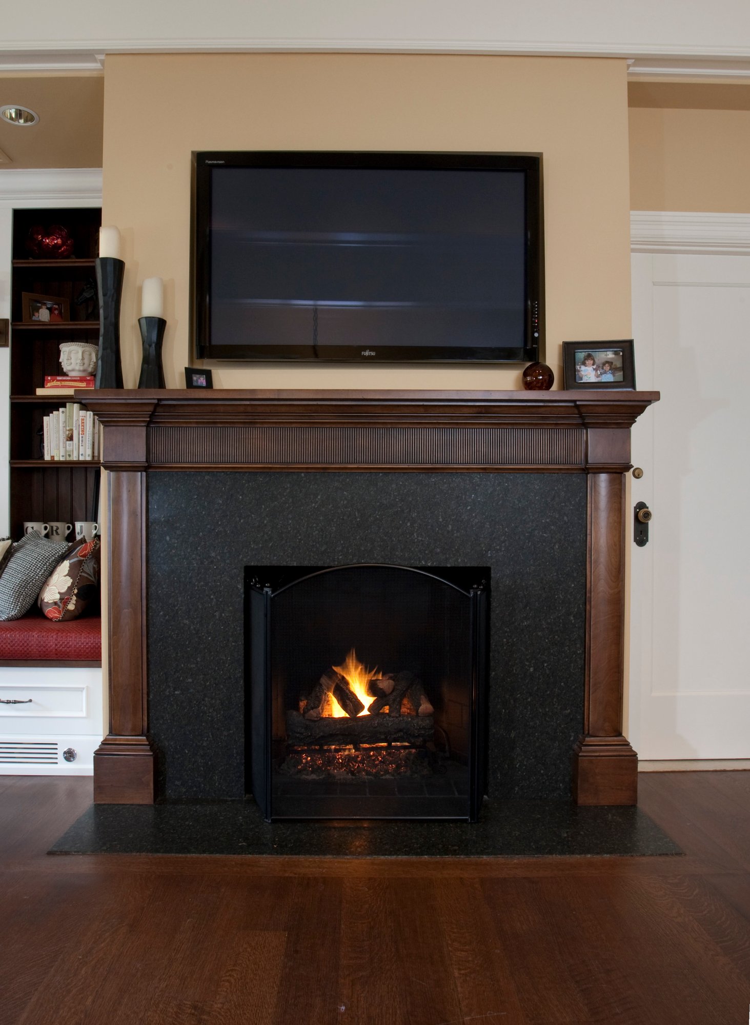 Front view of a custom fireplace with an oak wood trim, located within a home in Essex County, NJ, 