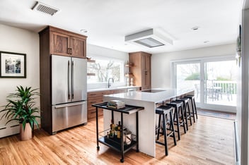 Remodeled kitchen with dark wood cabinets and waterfall island countertop