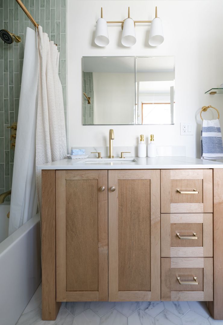 Elegant bathroom vanity with light wood cabinetry and brushed gold fixtures in Essex Fells, NJ by G&L and Sons Renovations