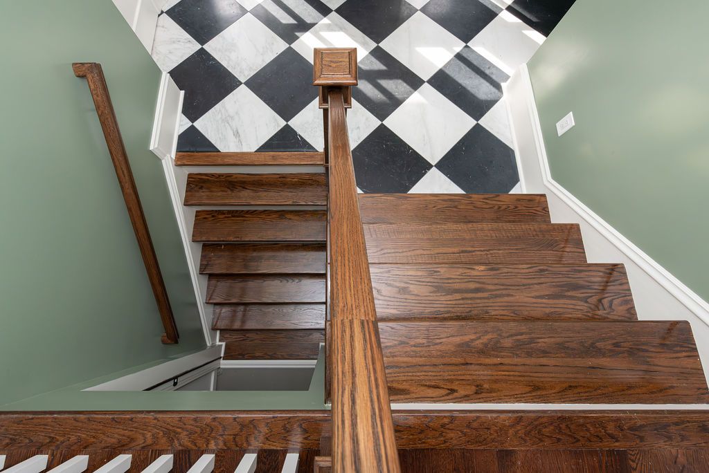 Refinished wood staircase with black and white checkered tile floor in Caldwell, NJ by G&L and Sons Renovations