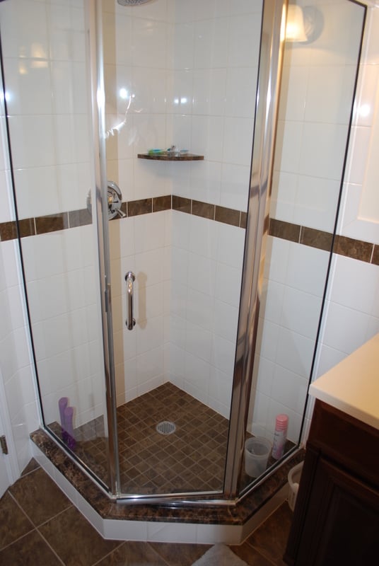 Compact corner shower with brown tile accents and glass enclosure by G&L and Sons Renovations in Fairfield, NJ