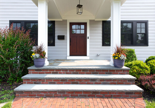 The front view of a single family home in Montclair, NJ, that shows the front door and a bay living room window. 