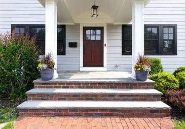 The front view of a single family home in Montclair, NJ, that shows the front door and a bay living room window. 