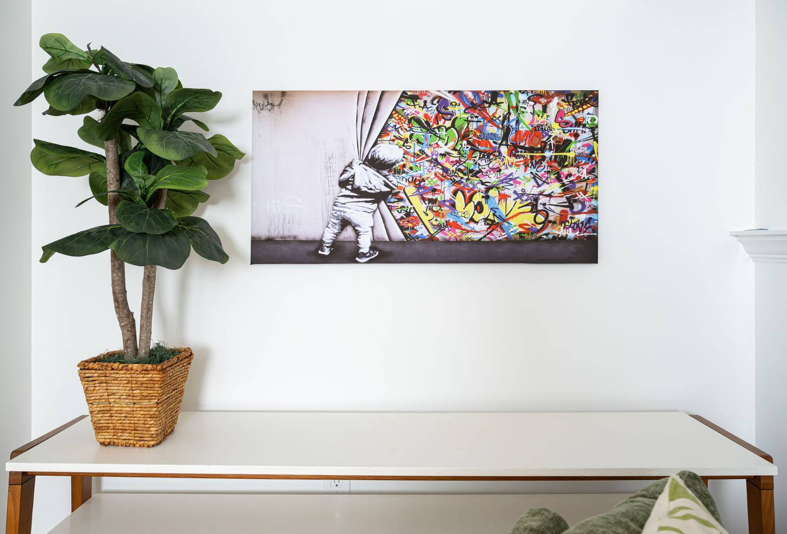 Minimalist wall art display with a child peeking behind a curtain of graffiti beside a tall potted plant. | G&L and Sons Renovations